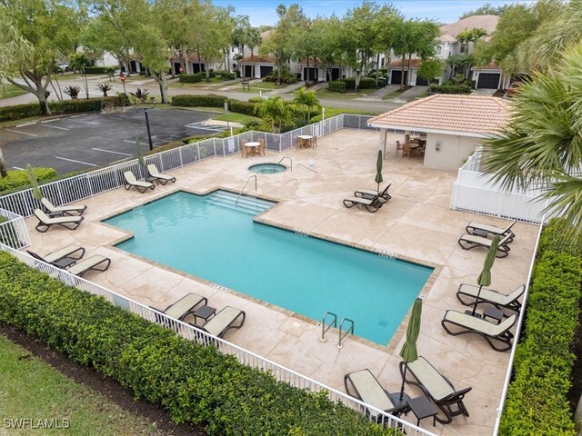 pool with a residential view, a hot tub, a patio, and fence