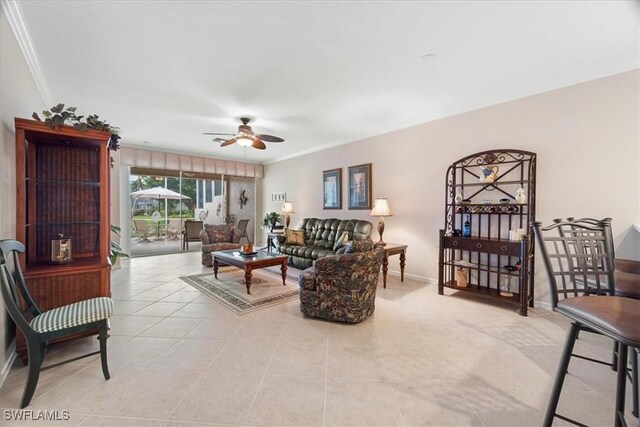 living area with crown molding, light tile patterned floors, baseboards, and ceiling fan