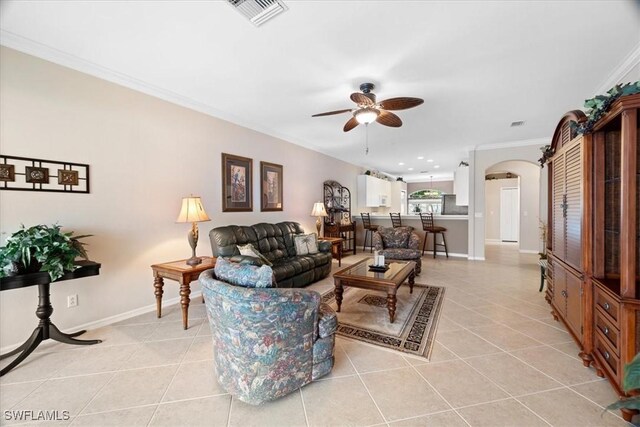 living room with visible vents, ceiling fan, ornamental molding, light tile patterned floors, and arched walkways