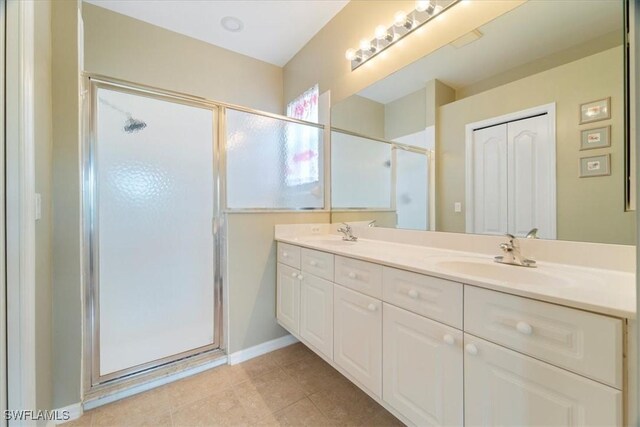 full bathroom with a sink, double vanity, a shower stall, and tile patterned floors