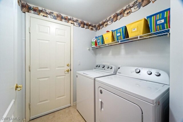 washroom featuring light tile patterned floors, laundry area, and washing machine and dryer