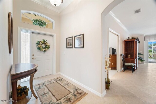 entrance foyer featuring light tile patterned flooring, visible vents, arched walkways, and ornamental molding