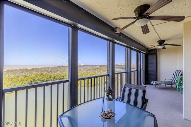 sunroom / solarium with outdoor dining space, ceiling fan, and a water view