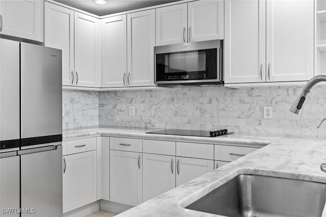 kitchen with open shelves, stainless steel appliances, light stone countertops, and white cabinetry