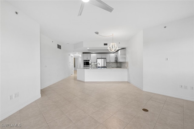 unfurnished living room with visible vents, baseboards, and ceiling fan