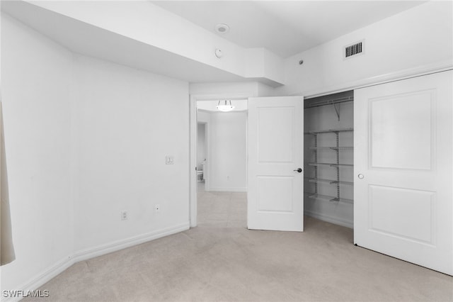 unfurnished bedroom with a closet, visible vents, light colored carpet, and baseboards