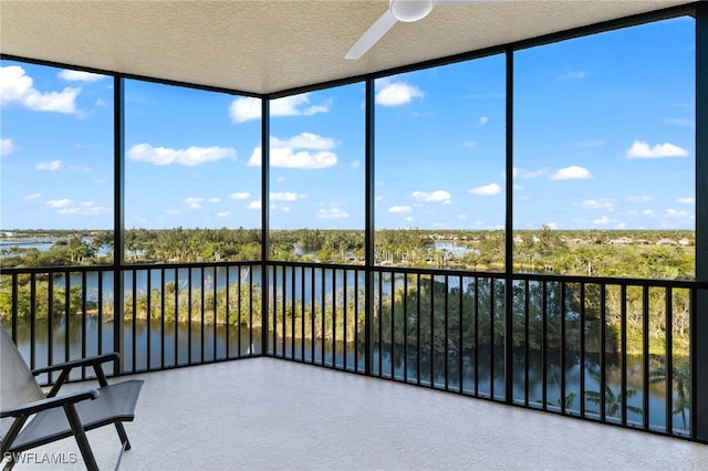 unfurnished sunroom with a ceiling fan and a water view