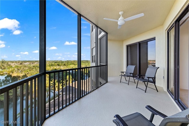 sunroom featuring a ceiling fan and a water view