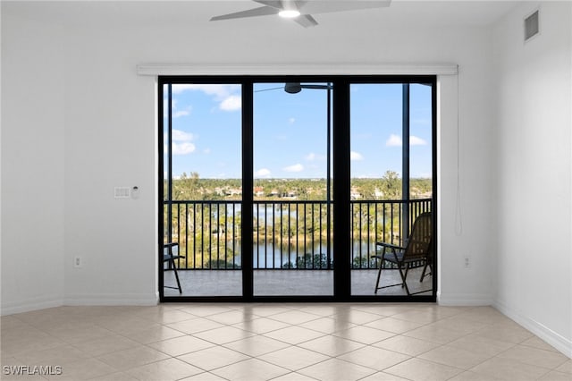 empty room with a ceiling fan, visible vents, a water view, and baseboards