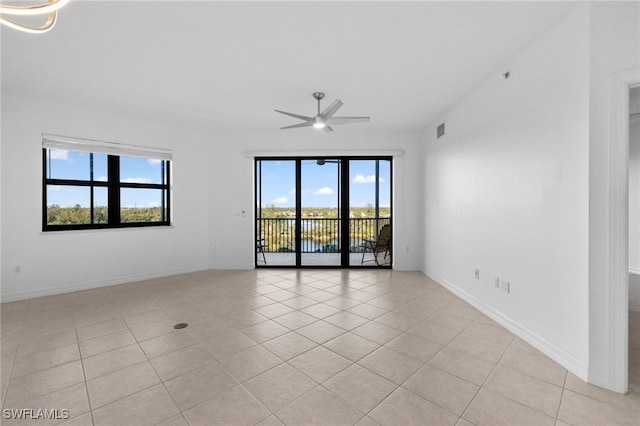 empty room featuring light tile patterned floors, visible vents, baseboards, and a ceiling fan