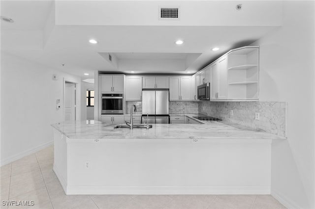 kitchen featuring visible vents, decorative backsplash, a peninsula, stainless steel appliances, and a sink