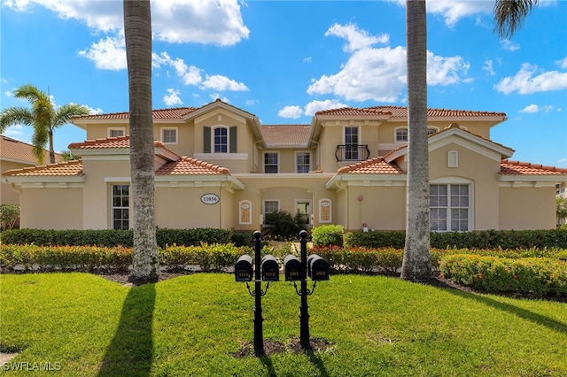 view of front of property featuring a front yard, a tiled roof, and stucco siding