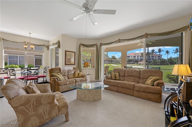 living room with ceiling fan with notable chandelier, carpet flooring, and a healthy amount of sunlight