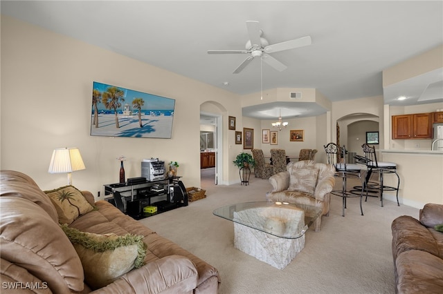 living area with arched walkways, visible vents, light carpet, and ceiling fan with notable chandelier