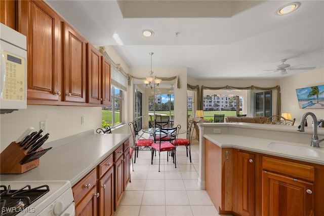 kitchen with white microwave, a wealth of natural light, a sink, and light countertops