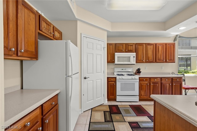 kitchen featuring white appliances, light tile patterned flooring, light countertops, and brown cabinetry