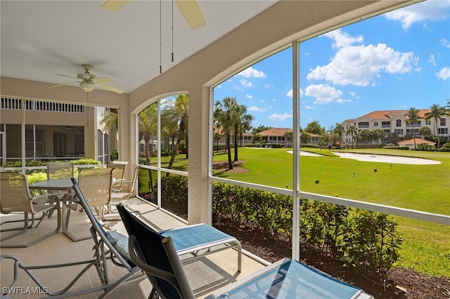 sunroom featuring ceiling fan and a residential view