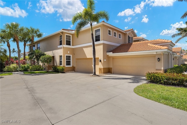 view of front of house with concrete driveway, a tile roof, and stucco siding