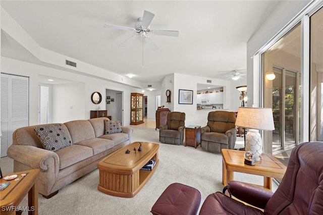 living room with decorative columns, carpet, visible vents, and ceiling fan