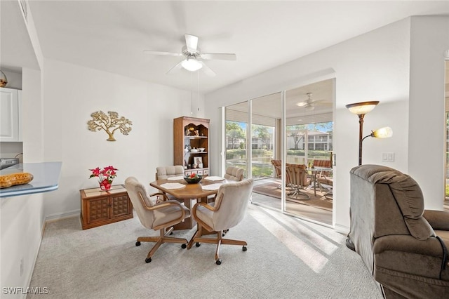 dining space featuring baseboards, light colored carpet, and a ceiling fan