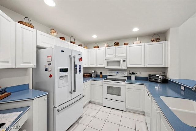 kitchen featuring a sink, white appliances, white cabinets, and light tile patterned floors