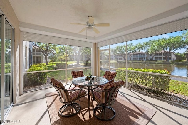 sunroom featuring a water view and a ceiling fan