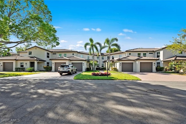 view of front of house with stucco siding, a tile roof, a residential view, and concrete driveway