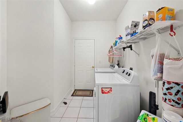 clothes washing area featuring baseboards, washer and clothes dryer, laundry area, and light tile patterned floors