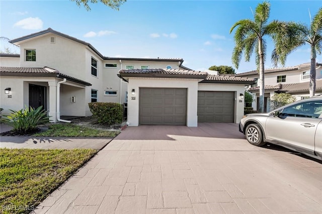 view of front of property featuring stucco siding, a garage, driveway, and a tile roof