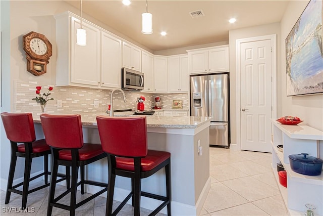 7658 Jacaranda Ln, Naples, FL 34114 - kitchen featuring visible vents, a peninsula, white cabinets, appliances with stainless steel finishes, and backsplash