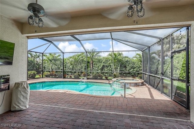 view of swimming pool with ceiling fan, a patio, glass enclosure, and a pool with connected hot tub