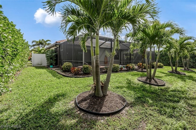 view of yard with glass enclosure and fence