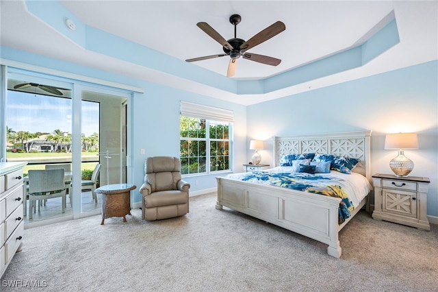 bedroom featuring carpet floors, access to exterior, and a raised ceiling