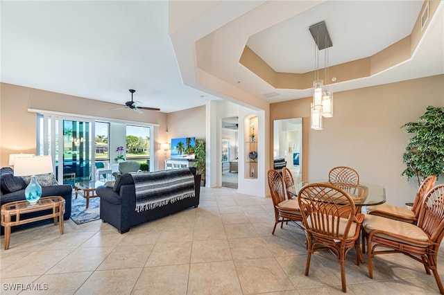 living room featuring a ceiling fan, a tray ceiling, visible vents, and light tile patterned flooring