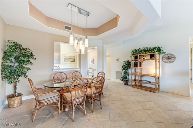 dining area featuring a tray ceiling, visible vents, baseboards, and light tile patterned flooring