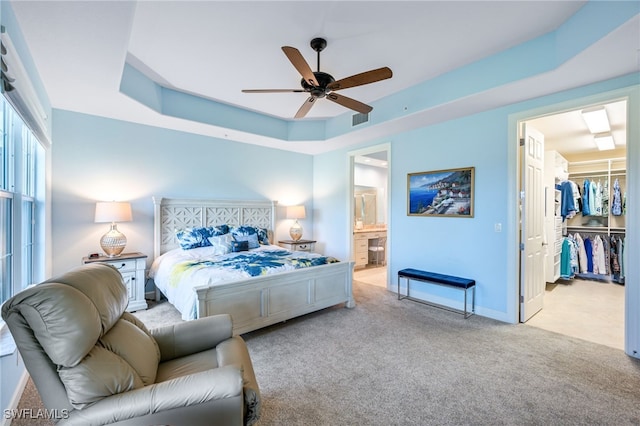 bedroom with carpet, a raised ceiling, visible vents, a spacious closet, and ensuite bath