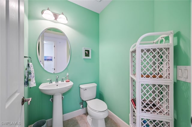 half bathroom featuring tile patterned flooring, toilet, and baseboards