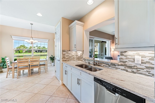 kitchen featuring light tile patterned floors, a sink, stainless steel dishwasher, light stone countertops, and pendant lighting