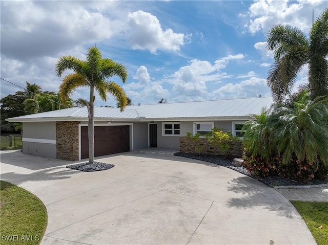 ranch-style home featuring a garage, concrete driveway, metal roof, and stucco siding