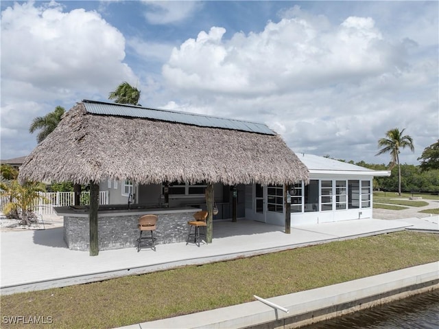 back of property featuring a patio, a sunroom, outdoor dry bar, fence, and a yard