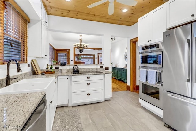 kitchen with appliances with stainless steel finishes, white cabinetry, a sink, light stone countertops, and wooden ceiling