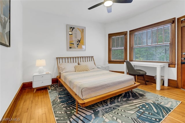 bedroom featuring ceiling fan, baseboards, and wood finished floors