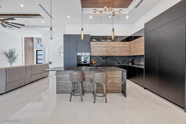 kitchen with modern cabinets, backsplash, a kitchen bar, pendant lighting, and a sink