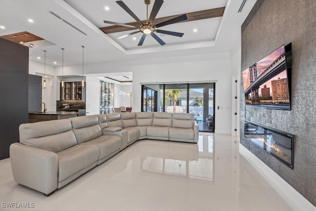 living area featuring a large fireplace, visible vents, a high ceiling, a tray ceiling, and recessed lighting