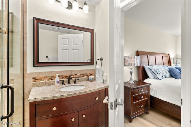 bathroom featuring vanity, ensuite bath, wood finished floors, and visible vents