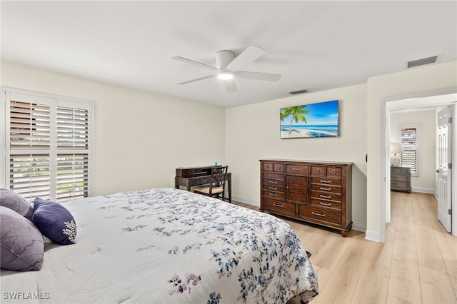 bedroom featuring visible vents, light wood-style flooring, a ceiling fan, and baseboards