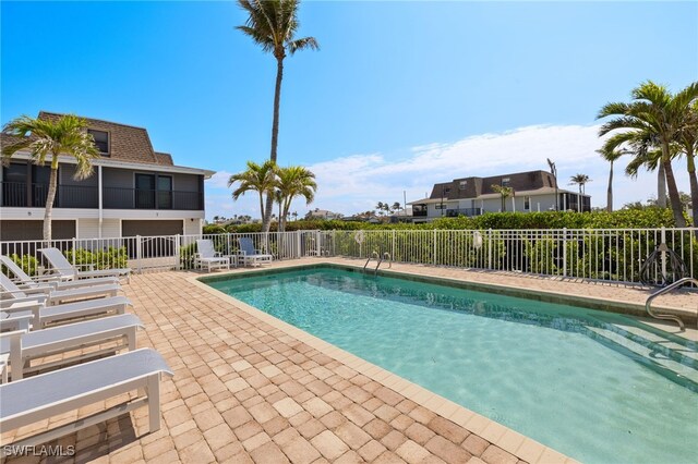 community pool with a patio area and fence