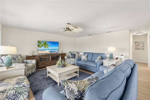 living area featuring a ceiling fan, wood finished floors, visible vents, and baseboards