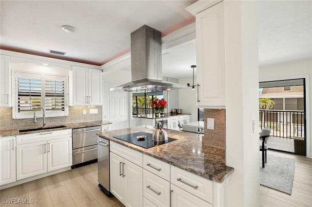 kitchen featuring dark stone counters, island exhaust hood, a sink, black electric cooktop, and backsplash