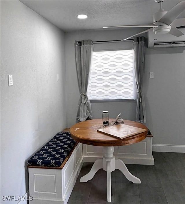 dining area with a textured ceiling, baseboards, and an AC wall unit